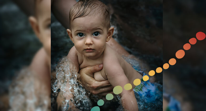 A baby in water with a person holding it