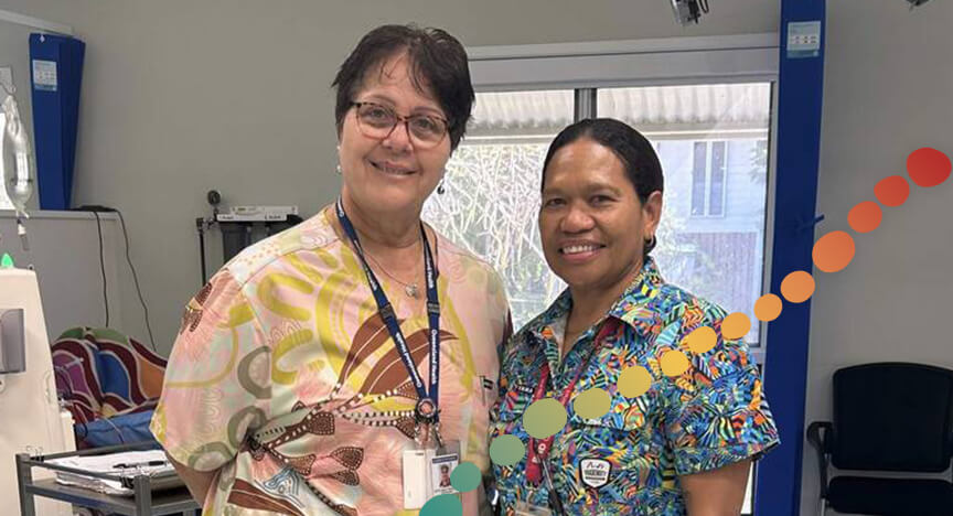 Two women pose for a photo, in a clinical room.