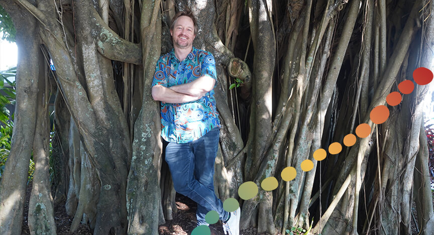 Man standing outside in front of a large tree