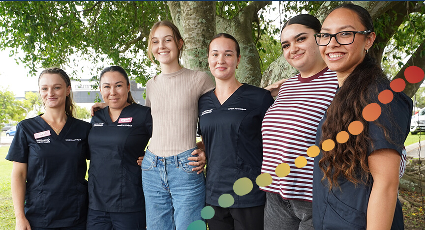 6 women standing together in front of a large tree