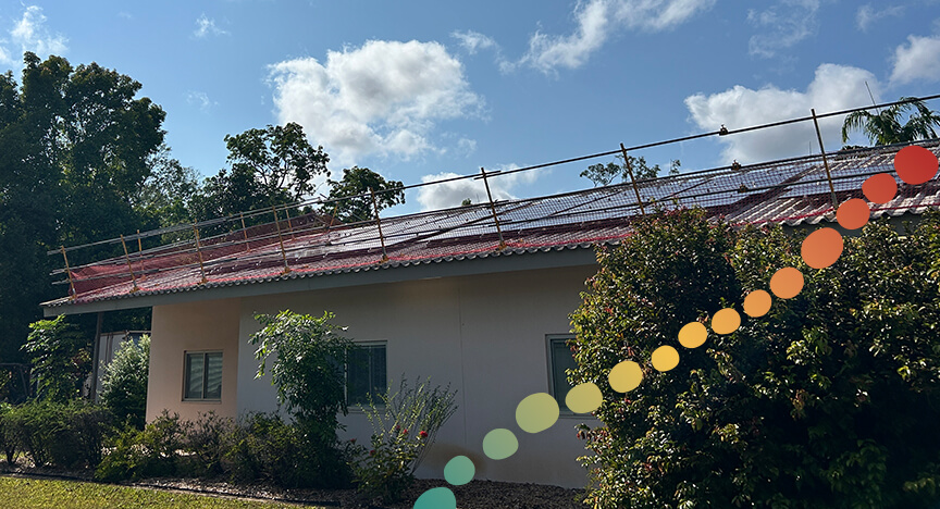 single storey building with solar panels being installed on roof.