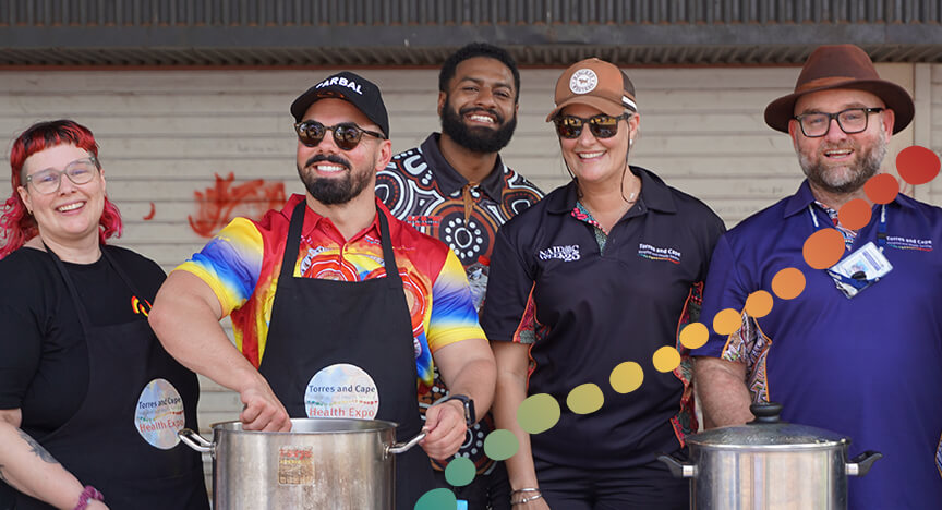 5 people standing behind a table, cooking