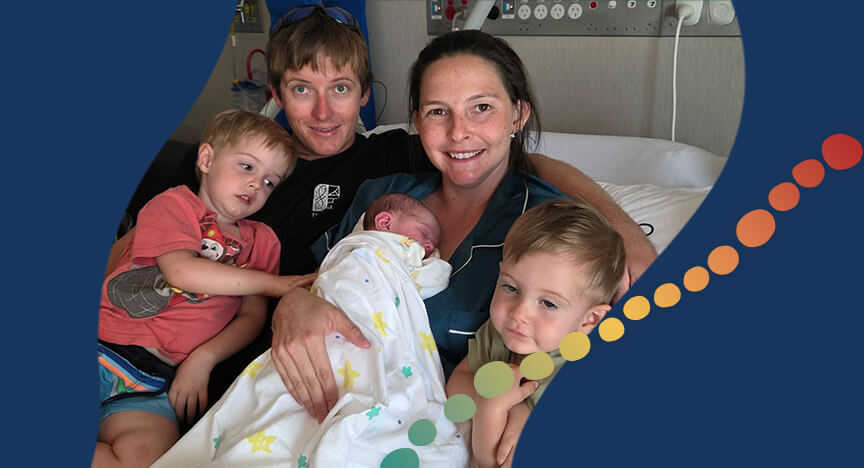 family together lying on a hospital bed with newborn child