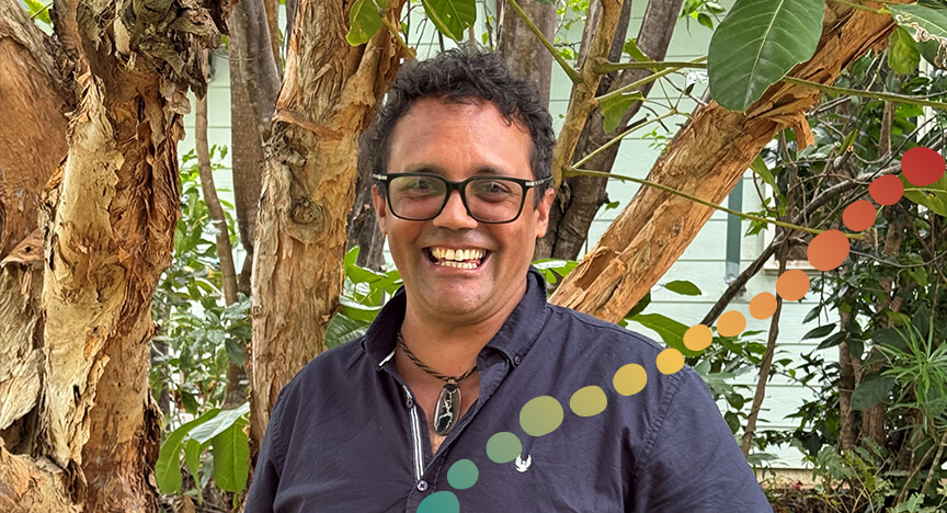 Man smiling, standing in front of trees