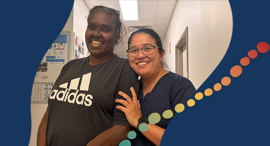 Two women pose for a photo, in a clinical room.